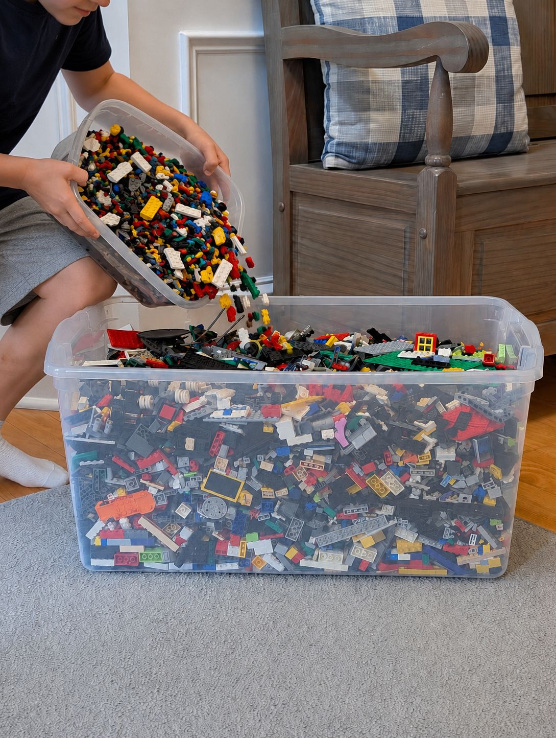 A parent and child pouring loose LEGO bricks into a shipping box together